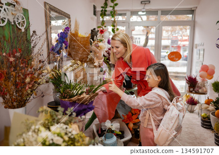 Mother and daughter explore vibrant flower shop, sharing joy and creativity on a sunny afternoon 134591707