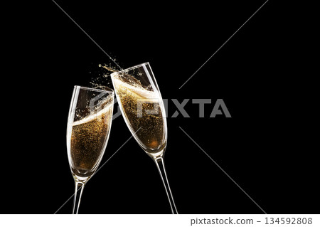 Two champagne flutes clinking in a festive toast. Golden bubbles and splashes against a dramatic black background. Elegant celebration, New Year, or wedding concept with copy space. Two champagne flutes clinking in a festive toast. Golden bubbles and splashes against a dramatic black background. Elegant celebration, New Year, or wedding concept with copy space. 134592808