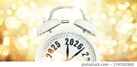 New Year 2026 countdown. White alarm clock showing transition from 2025 to 2026 with black numbers on a festive golden bokeh background. Celebration concept. New Year 2026 countdown. White alarm clock showing transition from 2025 to 2026 with black numbers on a festive golden bokeh background. Celebration concept. 134592868