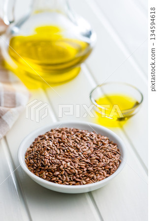 Brown linseed or flaxseed and oil. Healthy flax seed in bowl on white table. 134594618