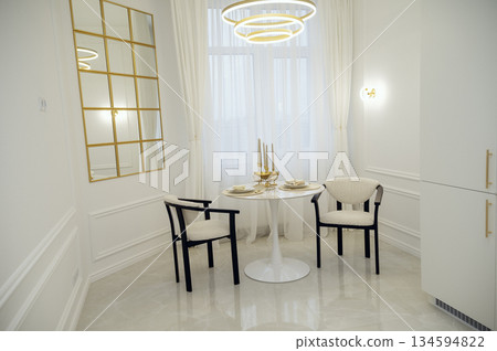 Bright modern dining room with white table, chairs and large refrigerator.  134594822