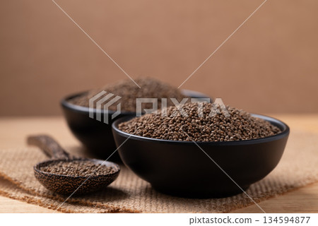 Dried perilla seed in black bowl with spoon on brown background 134594877