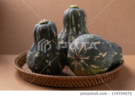 Green butternut squash pumpkin in basket on brown background Green butternut squash pumpkin in basket on brown background 134594878