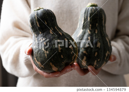 Green butternut squash pumpkin holding by woman hand Green butternut squash pumpkin holding by woman hand 134594879