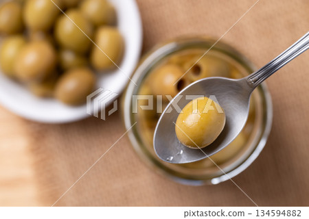 Pickled olives, Pitted green olives in spoon, Top view Pickled olives, Pitted green olives in spoon, Top view 134594882