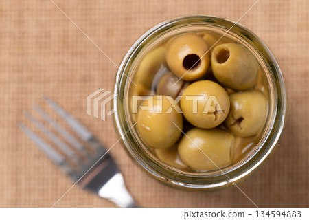 Pickled olives, Pitted green olives in glass jar, Top view Pickled olives, Pitted green olives in glass jar, Top view 134594883