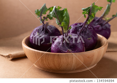 Purple kohlrabi or turnip cabbage in wooden bowl on brown background Purple kohlrabi or turnip cabbage in wooden bowl on brown background 134594894