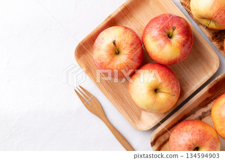 Red apple fruit (Gala apple) in natural plate with wooden fork on white background, Top view 134594903