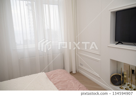 Bedroom interior, white decorative wall with TV, clock. 134594907