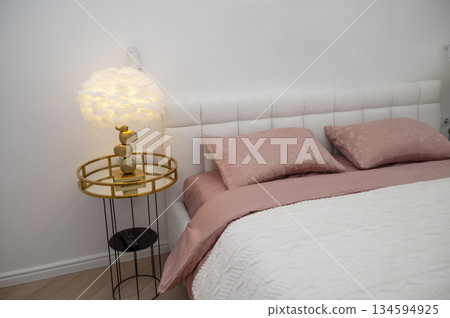 White double bed with dark pink bed linen and white blanket. 134594925