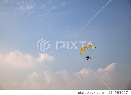 Flying on a paraglider with a propeller, an extreme kind of leisure. Parachuting, a man flying in the sky 134595637