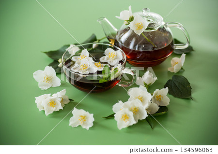 Brewed green tea with jasmine flowers top view Brewed green tea with jasmine flowers top view 134596063