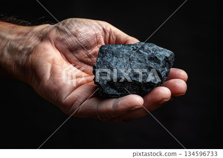 a hand man holds a black polymetallic nodule or Manganese Nodules to produce dark oxygen 134596733