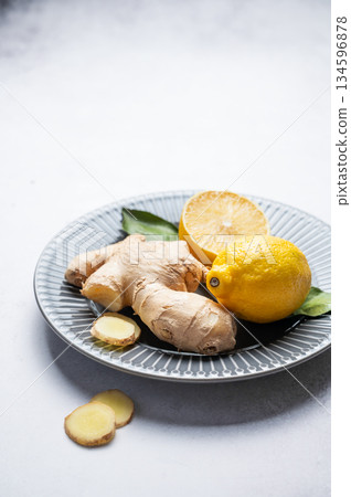 Sliced ginger root and lemon on a ceramic plate on  a light textured background. 134596878