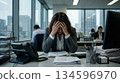 A depressed female office worker holding her head in the office 134596970