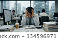 A depressed male office worker holding his head in the office 134596971