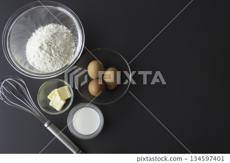 Ingredients for baking: flour, eggs, butter, milk and whisk. Flat lay. Ingredients for baking: flour, eggs, butter, milk and whisk. Flat lay. 134597401