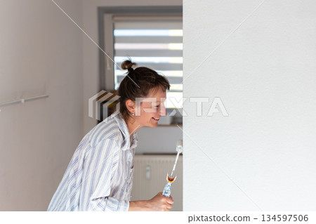 Scenic view happy young adult happy smiling woman portrait painting wall roller for moving in new house residential apartment with family. Casual lifestyle scene female person decorate living space Scenic view happy young adult happy smiling woman portrait painting wall roller for moving in new house residential apartment with family. Casual lifestyle scene female person decorate living space 134597506