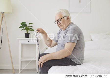 Thoughtful Elderly Man Sitting On Bed In Bedroom During Early Morning Routine 134598136