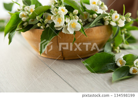 jasmine flowers in a wooden bowl on a light wooden background 134598199