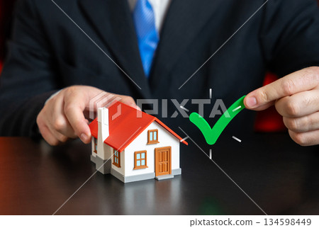 Check mark near his house. Green tick. Mortgage approval at a favorable interest rate. Favorable lending conditions. Banking trust. Successful loan approval. Home ownership. Check mark near his house. Green tick. Mortgage approval at a favorable interest rate. Favorable lending conditions. Banking trust. Successful loan approval. Home ownership. 134598449