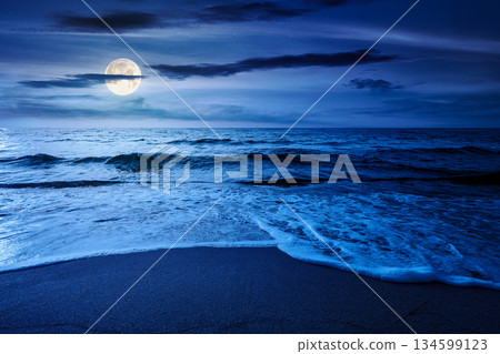 sand beach at the sea for summer vacation concept. beautiful night at perfect coast with calm waves and clouds on sky in full moon light. landscape for finance investment or abstract concepts 134599123