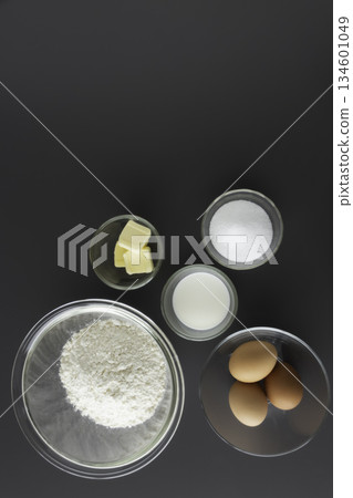 Ingredients for making sponge cake: flour, eggs, sugar, butter, milk. Bird's-eye view, vertical, blank space. Ingredients for making sponge cake: flour, eggs, sugar, butter, milk. Bird's-eye view, vertical, blank space. 134601049
