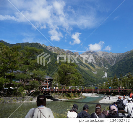 Crowds of tourists enjoying the scenery of the Azusa River and the Hotaka mountain range at Kappa Bridge, a popular autumn tourist spot in Kamikochi Crowds of tourists enjoying the scenery of the Azusa River and the Hotaka mountain range at Kappa Bridge, a popular autumn tourist spot in Kamikochi 134602752