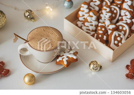 Cup of Hot Coffee with Christmas Gingerbread Cookies and Ornaments in Festive Setting 134603056