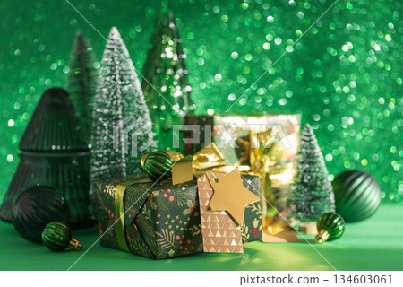 Christmas Gifts with Mini Trees and Green-Gold Ornaments on Festive Background Christmas Gifts with Mini Trees and Green-Gold Ornaments on Festive Background 134603061