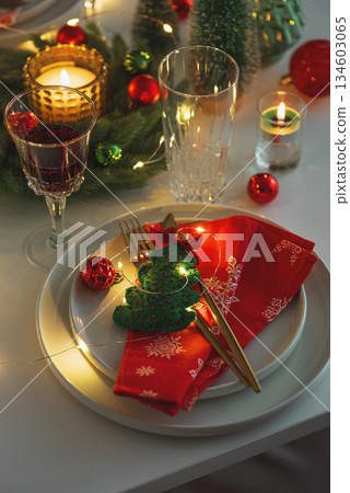 Christmas Table Setting with Red Napkin, Gold Cutlery, Felt Christmas Tree, Festive Decor and Candle Lights 134603065