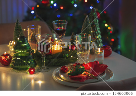 Festive Holiday Table Setting with Christmas Tree, Decorations and Candle Lights against Christmas Tree 134603066