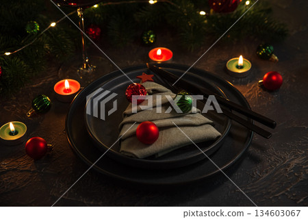 Christmas Table Setting with Tree-Shaped Napkin, Utensils, Ornaments and Tealight Candles Christmas Table Setting with Tree-Shaped Napkin, Utensils, Ornaments and Tealight Candles 134603067