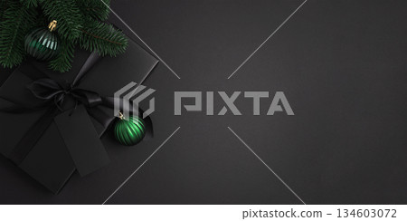 Black Christmas Gift Box with Satin Ribbon and Green Ornaments on Dark Holiday Background Black Christmas Gift Box with Satin Ribbon and Green Ornaments on Dark Holiday Background 134603072