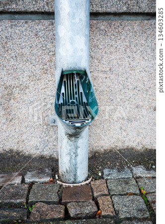Rainwater downspout with drain grate on stone pavement Rainwater downspout with drain grate on stone pavement 134603285