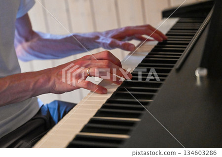 Hands playing piano keyboard in cozy home interior Hands playing piano keyboard in cozy home interior 134603286