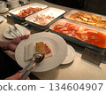He picked up a slice of ham from the hotel's upscale buffet. 134604907
