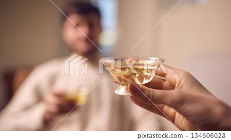 Hand holding glass cup of tea during quiet home tea ritual 134606028
