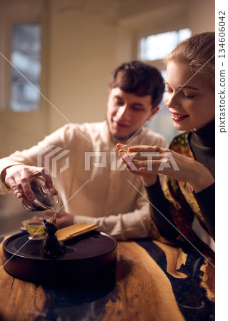 Man pouring hot tea during intimate tea ceremony with woman at home Man pouring hot tea during intimate tea ceremony with woman at home 134606042