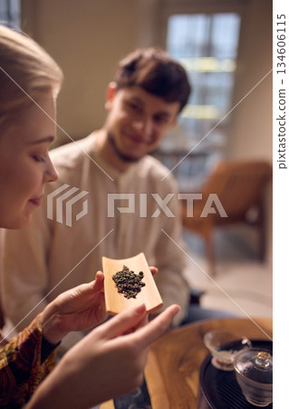 Woman holding tea leaves on wooden scoop during ceremony. 134606115