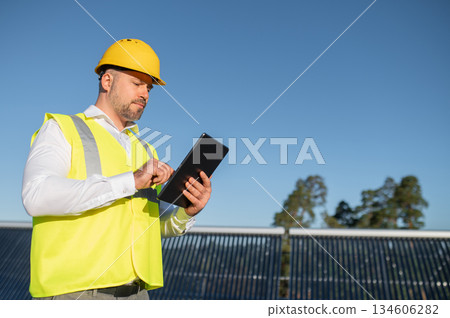 Technician using tablet to check photovoltaic system outdoors Technician using tablet to check photovoltaic system outdoors 134606282