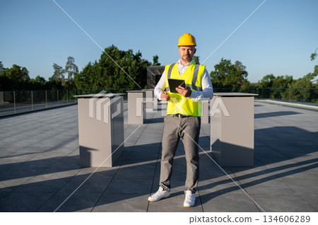 Worker inspecting rooftop solar panels holding digital tablet in hands Worker inspecting rooftop solar panels holding digital tablet in hands 134606289