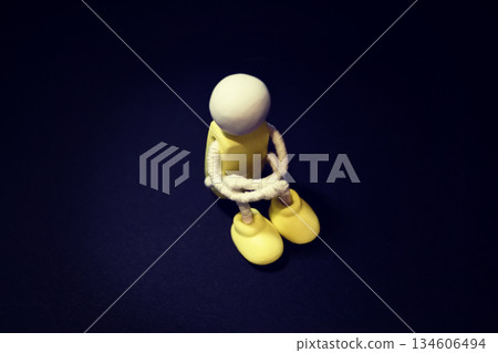 一張木偶抱著膝蓋的照片。照片中瀰漫著孤獨、沮喪、悔恨、悲傷和負面情緒。 134606494