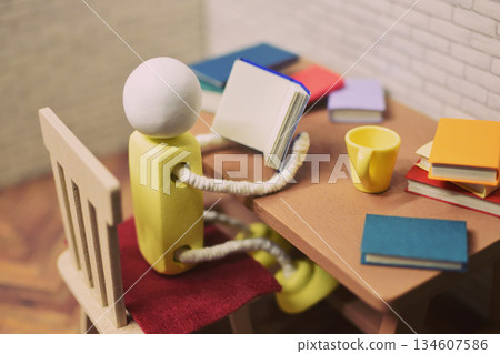 一張木偶閱讀的照片，周圍堆滿了書籍，業餘時間，學習，微縮模型 134607586