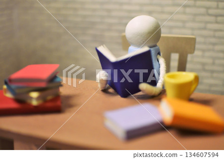 一張木偶閱讀的照片，周圍堆滿了書籍，業餘時間，學習，微縮模型 134607594