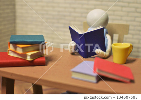 一張木偶閱讀的照片，周圍堆滿了書籍，業餘時間，學習，微縮模型 134607595