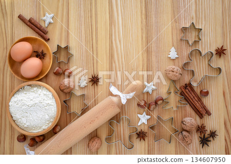 Holiday baking setup with flour, eggs, and festive cookie cutters on a wooden table Holiday baking setup with flour, eggs, and festive cookie cutters on a wooden table 134607950