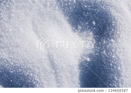 Winter holidays. Close-up of fresh sparkling snow under bright sun. Textured winter background with soft white drifts and deep blue shadows for contrast 134608387