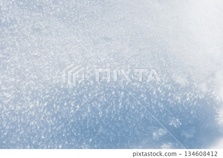 Close-up texture of fresh white snow with sparkling ice crystals. A cold, blue-toned winter background perfect for Christmas or New Year designs 134608412