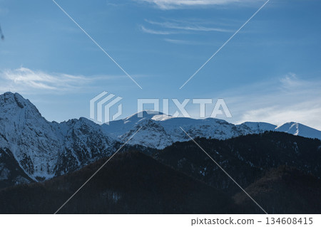 he stark beauty of the Tatras in winter. Sun-kissed snowy summits contrast sharply with the deep blue tones of the coniferous forests below he stark beauty of the Tatras in winter. Sun-kissed snowy summits contrast sharply with the deep blue tones of the coniferous forests below 134608415